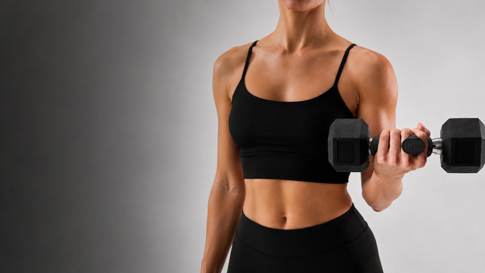 Mano de mujer levantando una mancuerna con el grip una, en un gimnasio luminoso